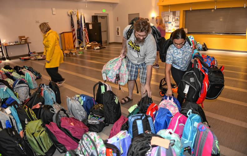 David Cole and Tanya Diaz of Community Action Pioneer Valley’s Family Center collect backpacks full of school supplies at the John Zon Community Center in Greenfield last week as part of the 20th annual Blooming Backpacks drive organized by Women’s Way, an affinity group of the local United Way of the Franklin & Hampshire Region.