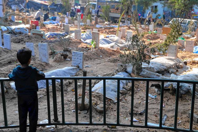 A Palestinian child looks at the graves of people killed in the Israeli bombardment of the Gaza Strip and buried inside the Shifa Hospital grounds in Gaza City on Dec. 31, 2023.