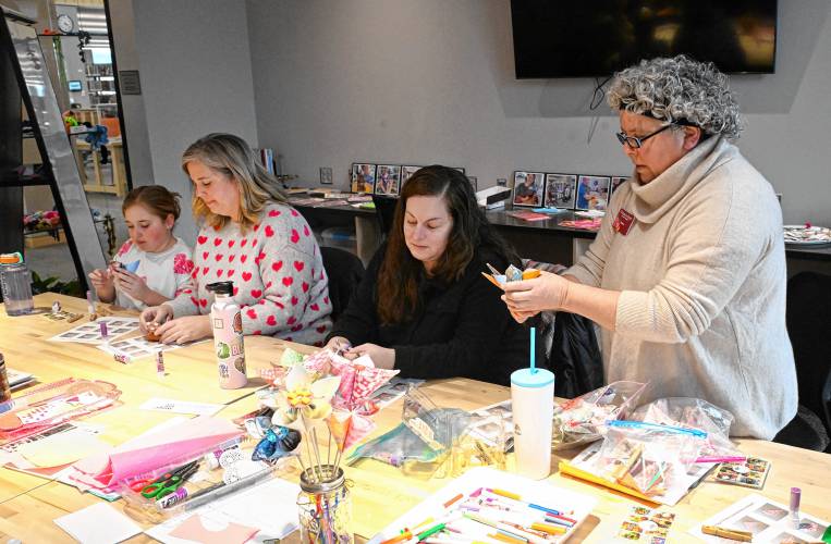 Paulina Borrego, right, runs a free workshop where participants learn how to make paper flowers in the Greenfield Public Library Makerspace on Friday. Participants learned folding and gluing skills to create a sustainable paper flower bouquet using origami paper and readily available materials. 