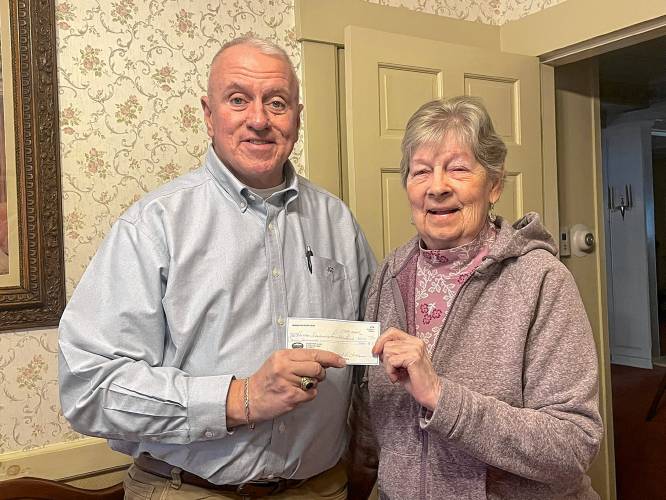 Jeff Cole, president of the Orange Scholarship Foundation, receives a check for $9,000 from Muriel Holden, co-chair of the Mahar 50+ Club. This brings total donations from the alumni group to the Orange Scholarship Foundation to more than $50,000 in the past 10 years.