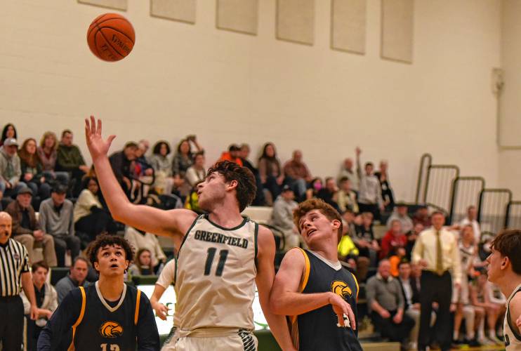 Greenfield’s Jon Breor (11) tries to grab a rebound next to Hopkins Academy’s James Fitzgibbons, right, during the Green Wave’s Hampshire League South victory at Nichols Gymnasium in Greenfield on Friday night.