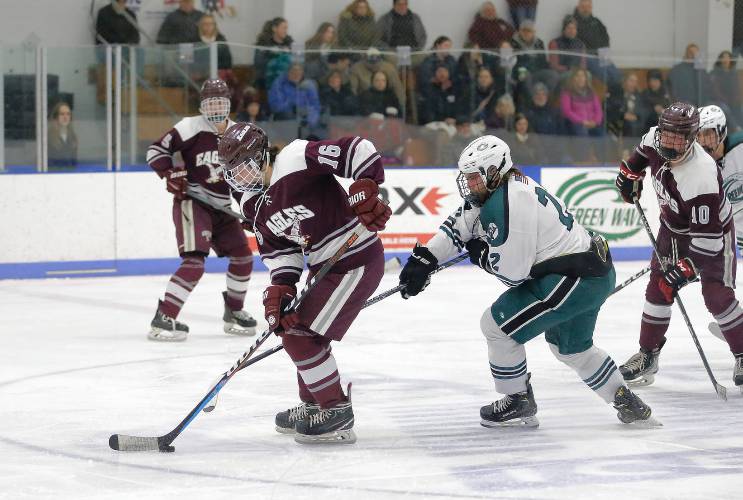 Easthampton’s Rob Herman (16) carries the puck up the ice under pressure from Greenfield’s Derek Wissman (22) in the second period Saturday night at Collins-Moylan Arena in Greenfield.