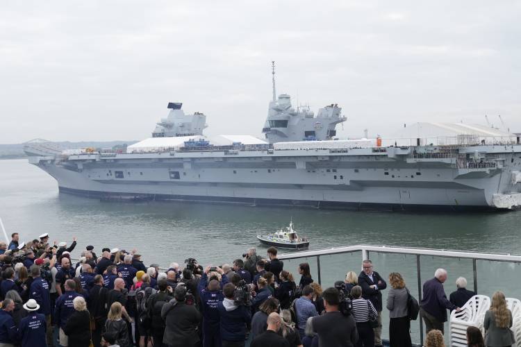 British Normandy veterans wave to the crowds and to the aircraft carrier HMS Prince of Wales that has its sides lined with sailors as they depart Portsmouth Harbour on board the Mont St Michael ferry to France, in Portsmouth England, Tuesday, June 4, 2024.