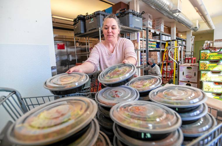 Warehouse Resource Manager Amy Vaccarella places pre-made meals into a cart at the Northampton Survival Center. The Survival Center is partnering with La Veracruzana and Uya Poke Bowl to provide more than 2,800 meals.