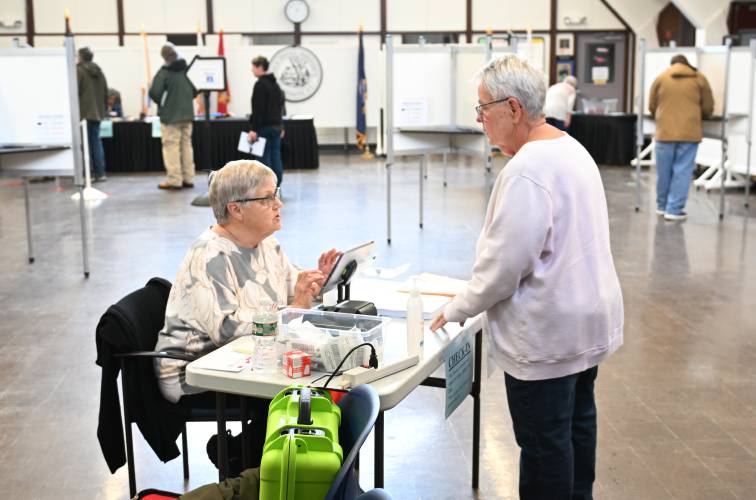 Election worker Nora Owens checks resident Debra Wojtowicz in to vote at Deerfield Town Hall on Monday.