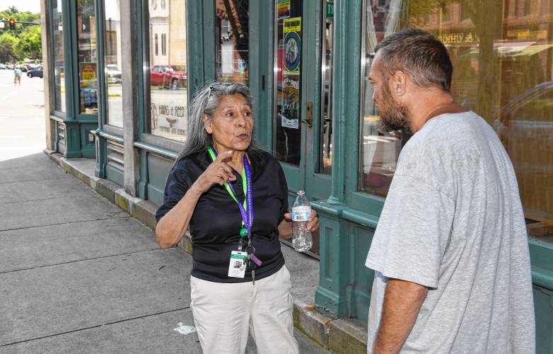 Maria Burge, community liaison for the Greenfield Police Department, talks with Greenfield resident Patrick Rooney on Main Street on Friday.