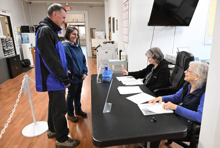 Bernardston residents Joel and Susan Finnell are checked in to vote by election workers Judy Beckwith and Beth Gildin Watrous in Bernardston Town Hall on Monday. 