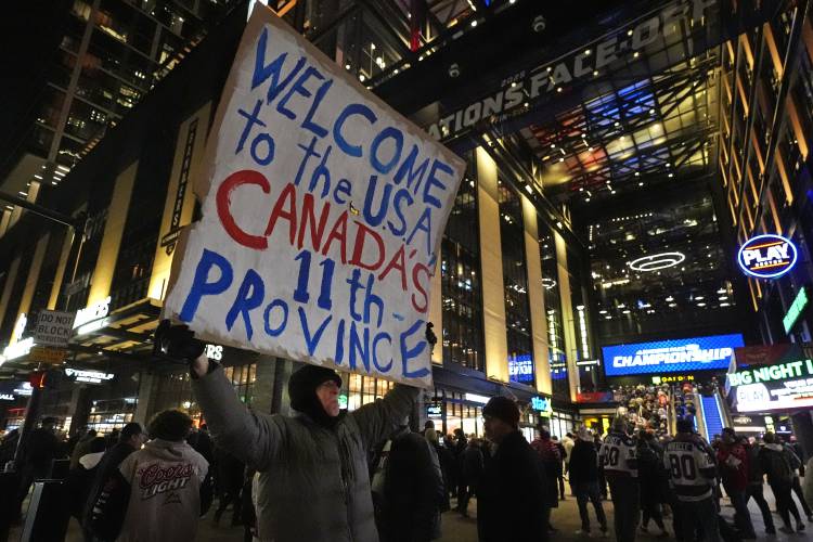 As fans enter the Boston Garden, a man holds a sign on the sidewalk prior to the 4 Nations Face-Off championship hockey game between the United States and Canada, Thursday, Feb. 20, 2025, in Boston. (AP Photo/Charles Krupa)