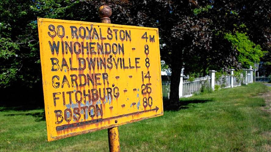 Distances to cities and towns are enumerated on a vintage road sign in Royalston.