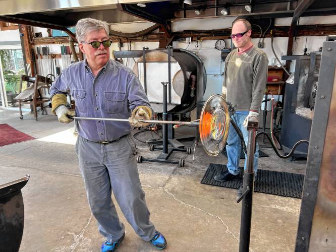 Shelburne glass artist Josh Simpson spins out a clear glass disc while contributing to the Buckland Historical Society’s Wilder Homestead restoration project.