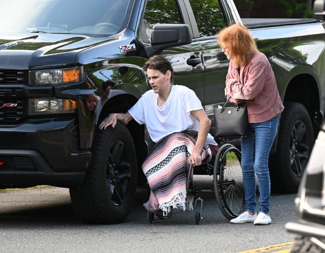 Chester Bai, who says he was attacked in his home at 221 Elm St. in Greenfield, with his mother Kathleen Lovett, waits while police stage outside his home with the alleged attacker still inside.