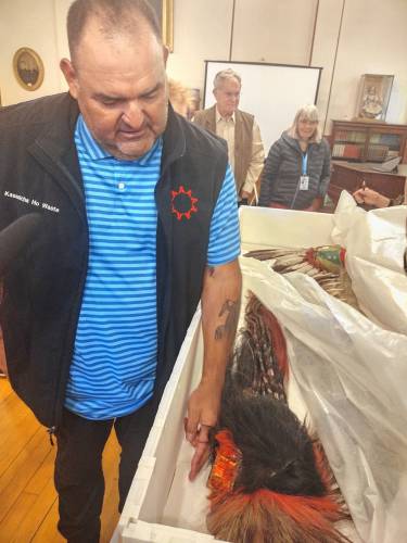 Justin Pourier, fifth member and tribal historic preservation officer of the Oglala Sioux Tribe, examines one of the headdresses being returned by the Woods Memorial Library during a ceremony in Barre on Monday.