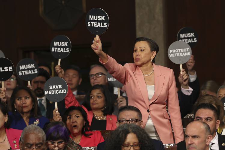 Rep. Nydia Velazquez, D-N.Y., holds a protest sign with fellow Democrats as President Donald Trump addresses a joint session of Congress at the Capitol in Washington, Tuesday, March 4, 2025. (Win McNamee/Pool Photo via AP)