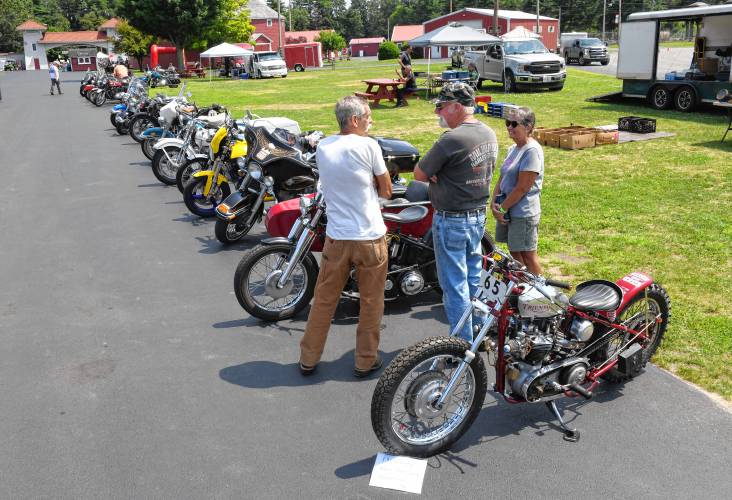 Antique motorcycle enthusiasts check out rows of vintage bikes, including the 1950 Triumph dirt drag racer in front, on Friday during an event at the Franklin County Fairgrounds in Greenfield celebrating the 70th year of the Antique Motorcycle Club of America.