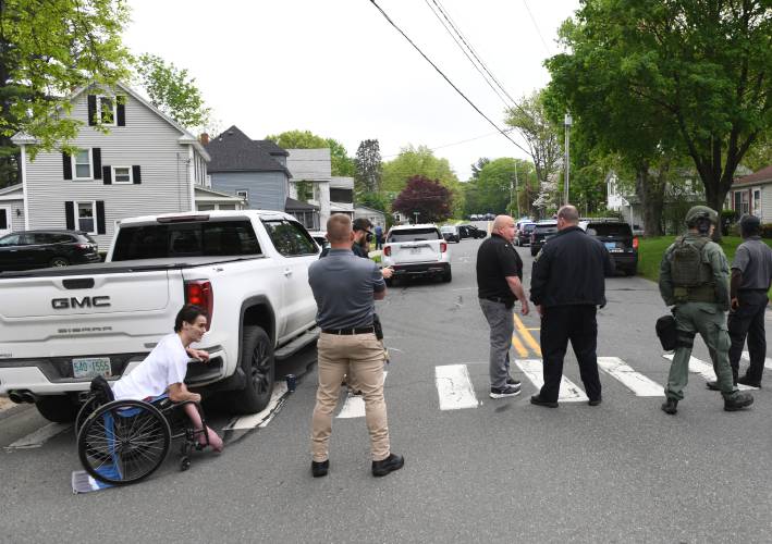 At left, Chester Bai, who says he was attacked in his home at 221 Elm St., talks with Greenfield Police Chief Todd Dodge on Friday while police stage outside his home while the alleged attacker was still inside.