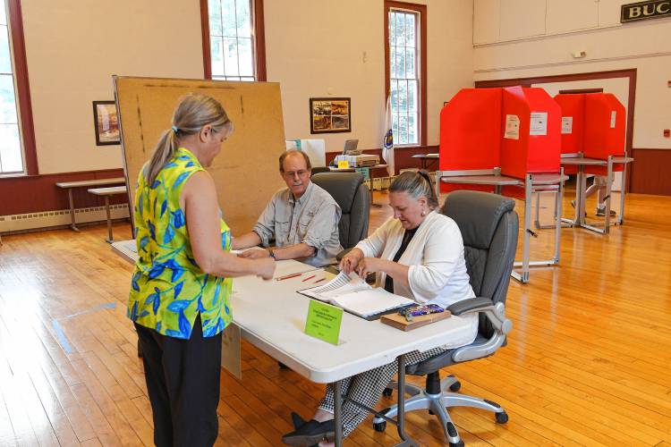 Resident Doris Schload is checked in to vote by election worker John Gyster and Town Clerk Alicia Graves on Tuesday in Buckland Town Hall.