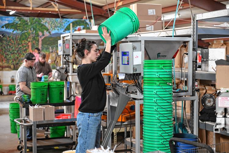 Worker/owner Elena Kuhn fills a hopper with roasted beans for bagging coffee at Dean’s Beans Organic Coffee Co. in Orange.