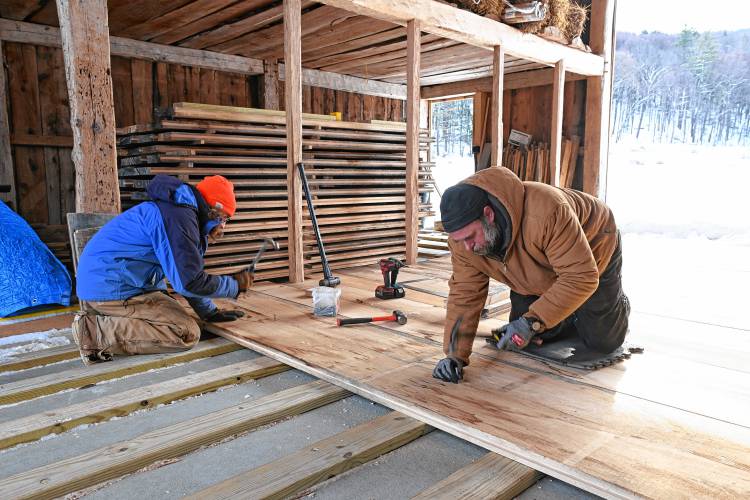 Zane Provost of Leverett and Vasilios Katsavrias of Buckland hammer galvanized cut nails into 2-inch pine floor boards in the rebuilt barn at the Wilder Homestead in Buckland.
