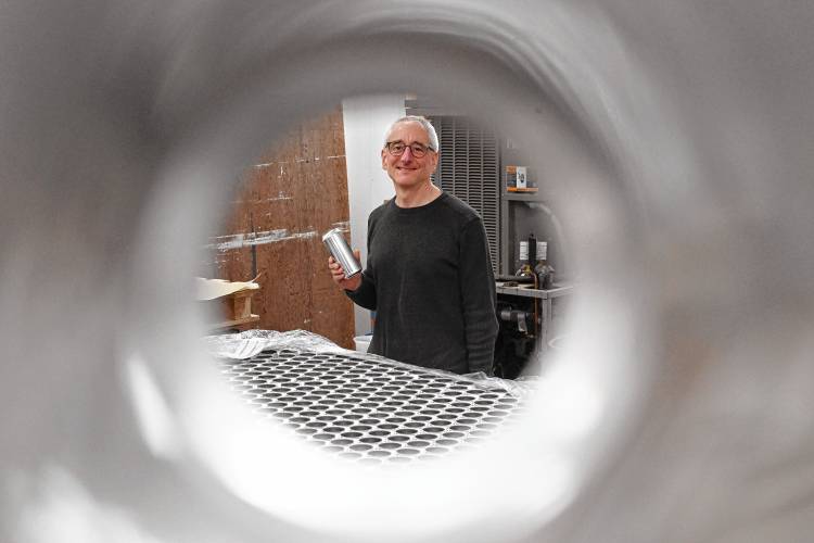 Dan Kramer, of Element Brewing Co. in Millers Falls, seen looking through an aluminum can.