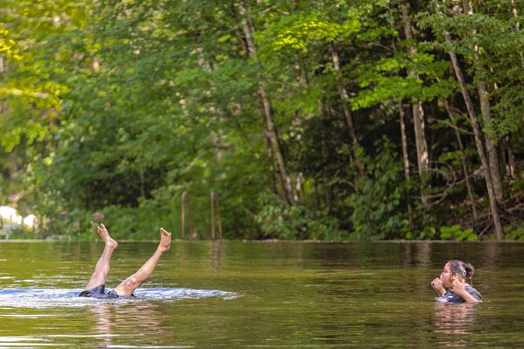 A swimmer does a hand stand in the Cold River at the Cold River Pool/Beach Area at the Mohawk State Forest in Charlemont while another swimmer looks on.