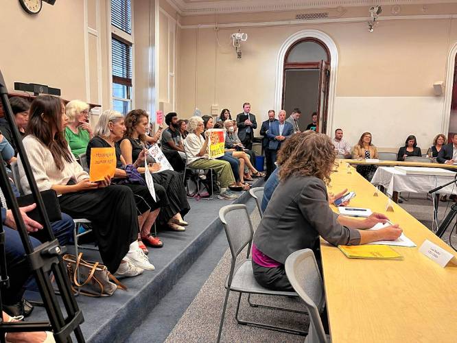 Activists hold signs in protest of shelter restrictions at a meeting of the special commission on Emergency Assistance family shelter on Monday.