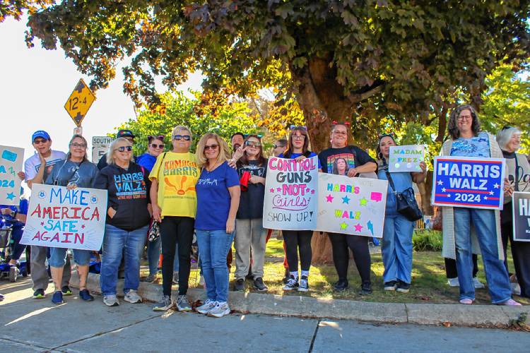 A group of demonstrators gathers at the Greenfield Common on Saturday afternoon to show their support for the Harris-Walz campaign. Rally organizers Ashleigh Young and Amanda Brown are pictured in the center, with Young holding a “Control Guns, Not Girls” sign, with Brown to her right.