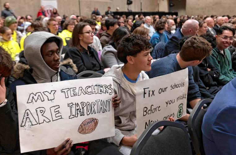 Rajahni Conyers and Fernando Aguila, Amherst Regional High School students, hold signs inside the UMass Campus Center where a hearing of the Joint Committee on Ways and Means took place on Monday. 